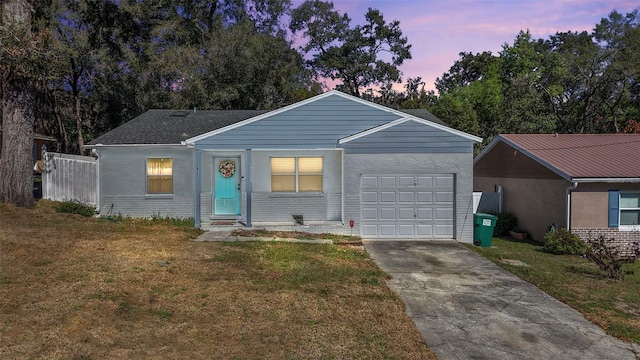 single story home featuring brick siding, an attached garage, a front yard, fence, and driveway