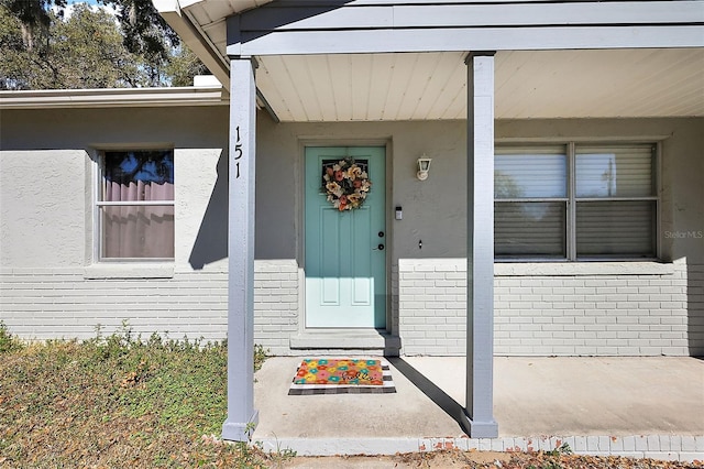 property entrance with stucco siding and brick siding