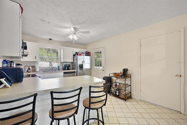 kitchen with a peninsula, white cabinetry, a kitchen breakfast bar, light countertops, and appliances with stainless steel finishes