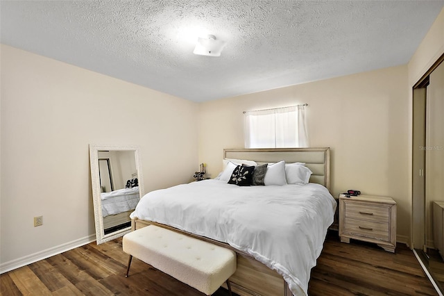 bedroom with dark wood-style floors, baseboards, and a textured ceiling