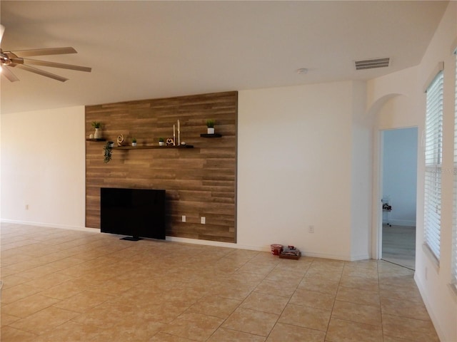 unfurnished living room with a ceiling fan, visible vents, baseboards, a fireplace, and tile patterned flooring