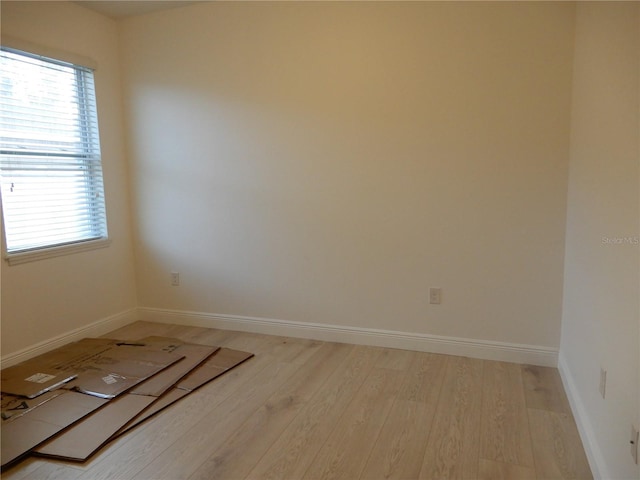 unfurnished room with light wood-type flooring and baseboards