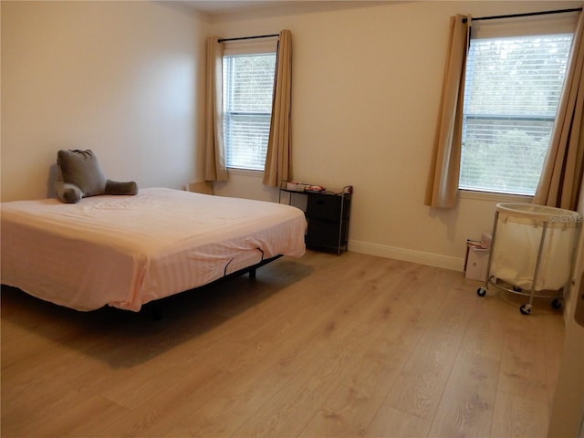 bedroom with light wood-style flooring and baseboards