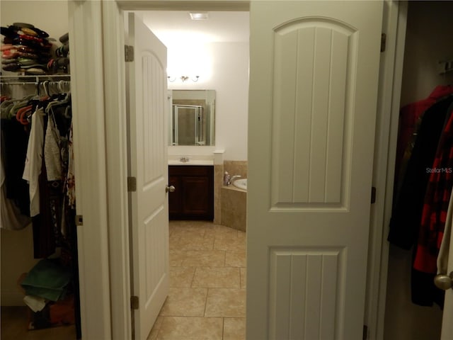 bathroom with a walk in closet, a shower stall, a bath, and vanity