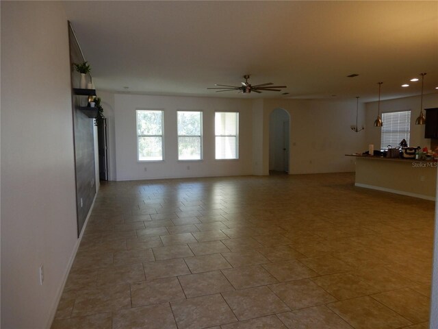 unfurnished living room with recessed lighting, arched walkways, and ceiling fan