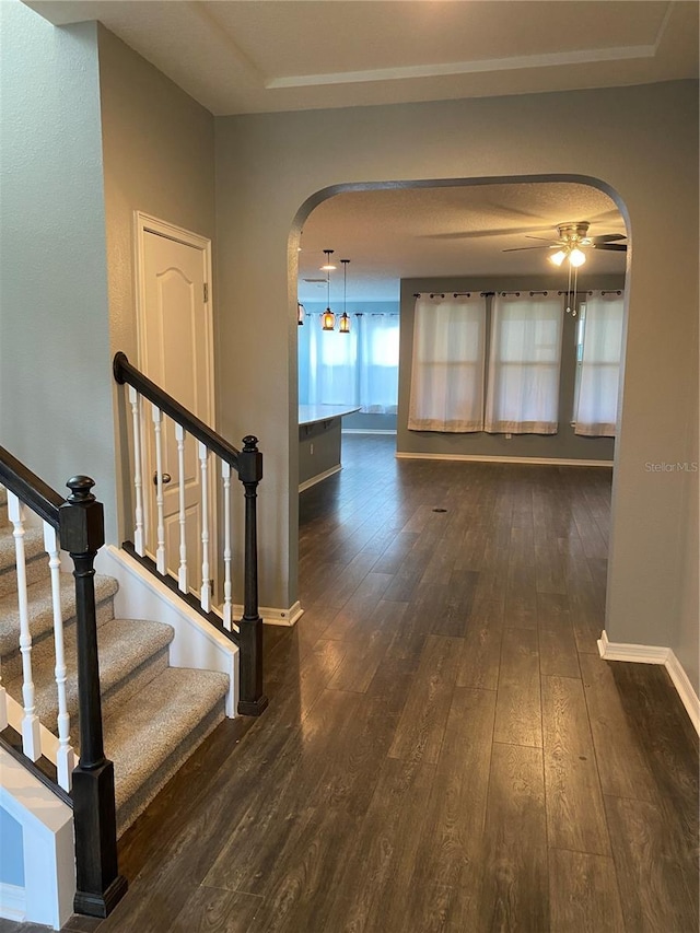 interior space with dark wood-style floors, arched walkways, baseboards, and stairs