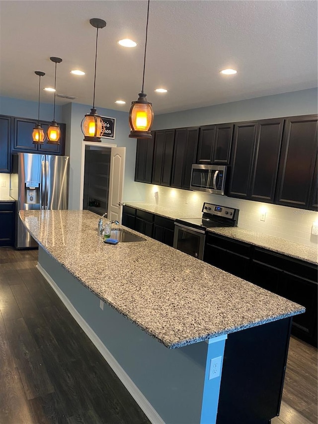 kitchen with stainless steel appliances, light stone counters, a sink, and dark wood finished floors