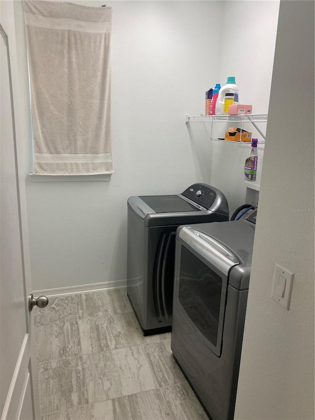 clothes washing area with laundry area, independent washer and dryer, and baseboards