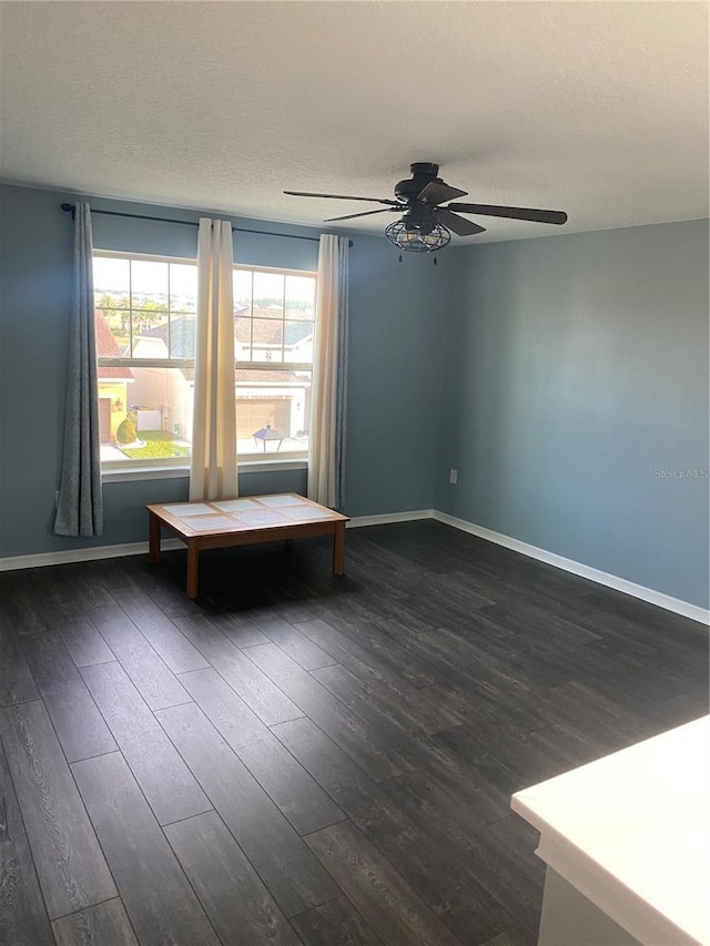 unfurnished room featuring dark wood-style flooring, a textured ceiling, and baseboards