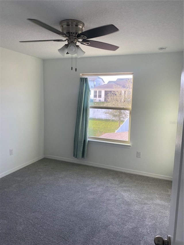 unfurnished room with a textured ceiling, carpet floors, a ceiling fan, and baseboards