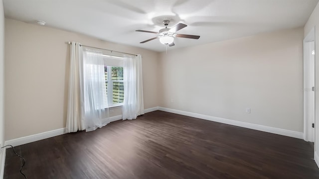 spare room with ceiling fan, dark wood-style flooring, and baseboards