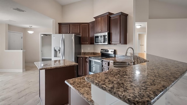 kitchen with dark brown cabinetry, visible vents, a kitchen island, stainless steel appliances, and a sink