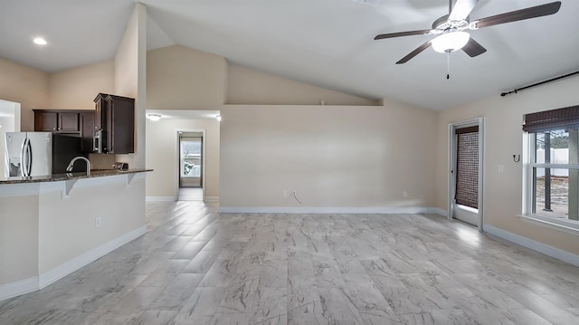 unfurnished living room featuring high vaulted ceiling, a sink, a ceiling fan, and baseboards