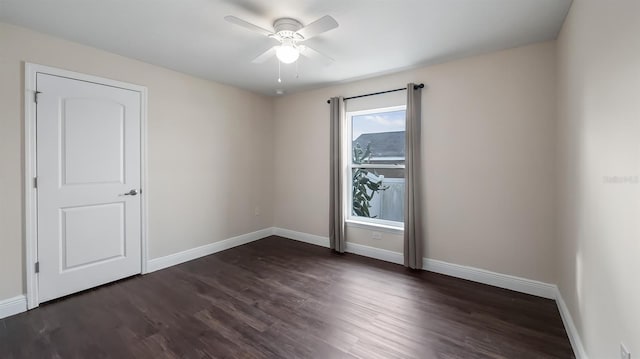 empty room with dark wood-style flooring, a ceiling fan, and baseboards