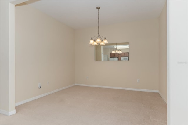 empty room featuring light carpet, baseboards, and an inviting chandelier