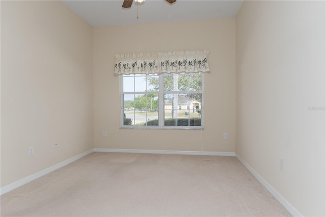 empty room with baseboards, a ceiling fan, and light colored carpet