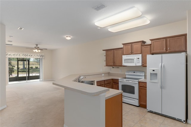 kitchen with a peninsula, white appliances, visible vents, light countertops, and brown cabinets