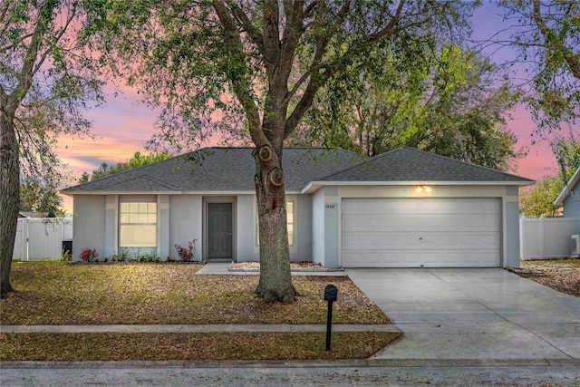 single story home featuring an attached garage, fence, concrete driveway, roof with shingles, and stucco siding