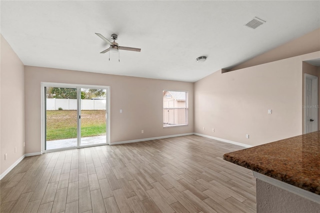 unfurnished living room with lofted ceiling, plenty of natural light, visible vents, and light wood-style floors