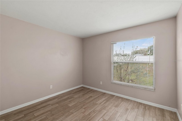 spare room featuring light wood-type flooring and baseboards