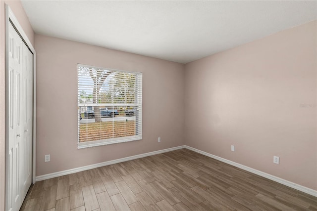 unfurnished bedroom featuring a closet, baseboards, and wood finished floors