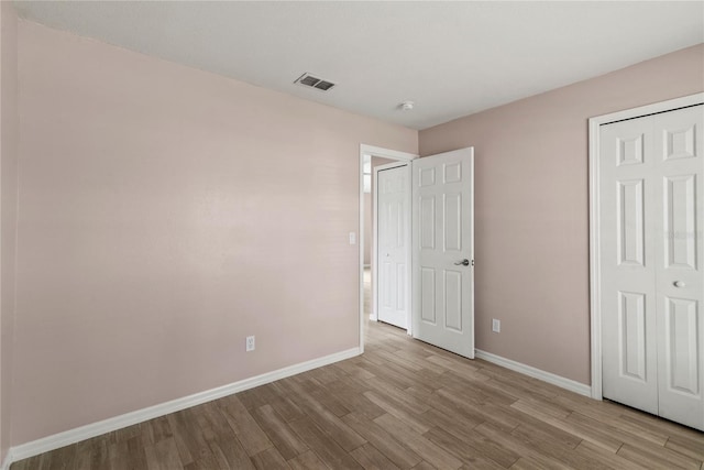 unfurnished bedroom featuring baseboards, visible vents, and wood finished floors