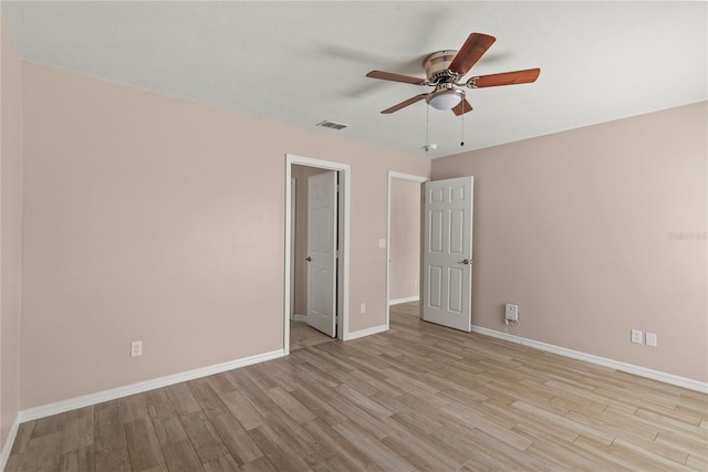 unfurnished room with light wood-type flooring, visible vents, baseboards, and a ceiling fan