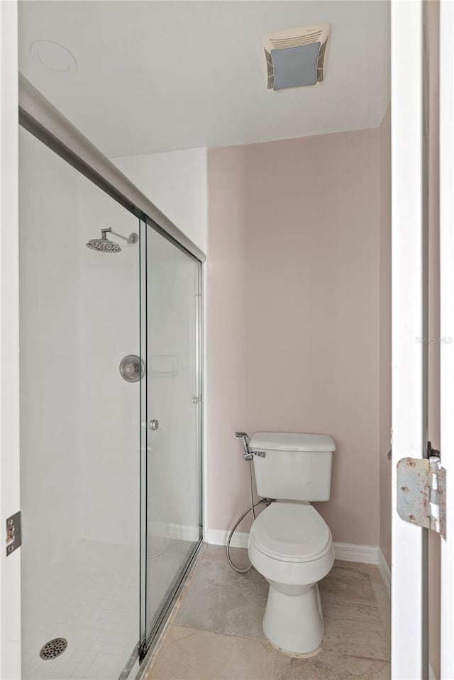 full bathroom featuring toilet, a shower stall, and baseboards