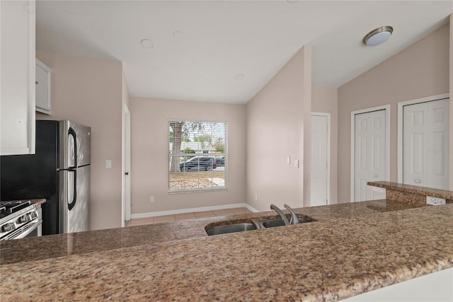 kitchen featuring lofted ceiling, a sink, white cabinets, and light stone countertops