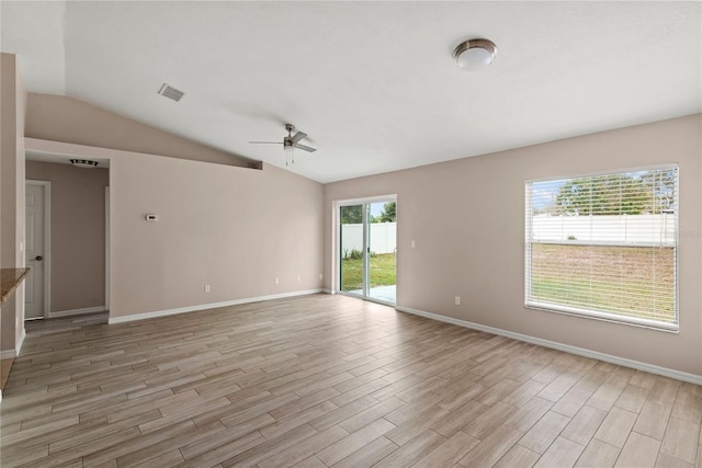 empty room with lofted ceiling, ceiling fan, visible vents, baseboards, and light wood finished floors