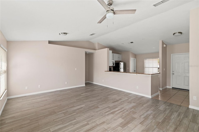 unfurnished living room featuring visible vents, baseboards, ceiling fan, vaulted ceiling, and light wood-style floors