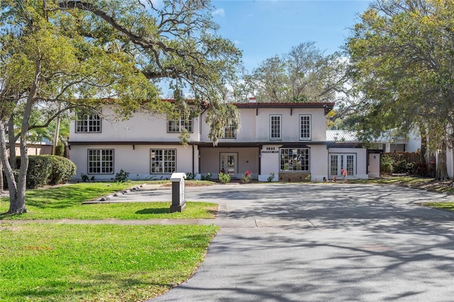 view of property with a front yard, french doors, and stucco siding