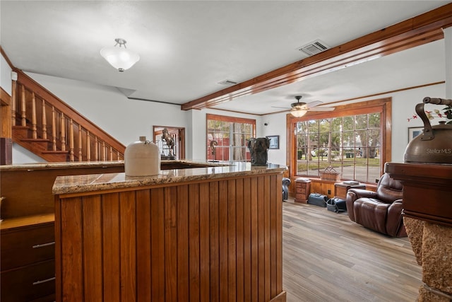 interior space with stone countertops, light wood-type flooring, beam ceiling, and visible vents