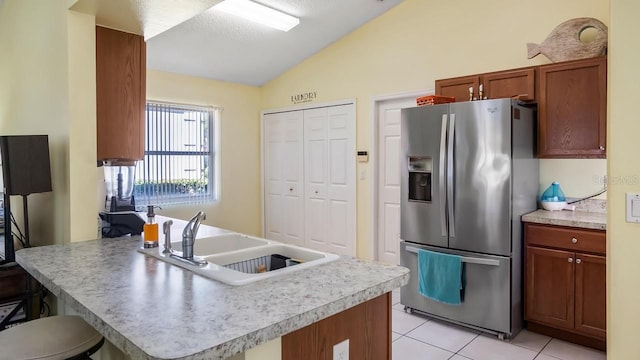 3773 Eversholt St, Clermont, FL 34711 - kitchen with vaulted ceiling, light tile patterned floors, a peninsula, stainless steel fridge, and a sink