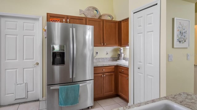 3773 Eversholt St, Clermont, FL 34711 - kitchen with light countertops, brown cabinetry, light tile patterned floors, and stainless steel fridge with ice dispenser