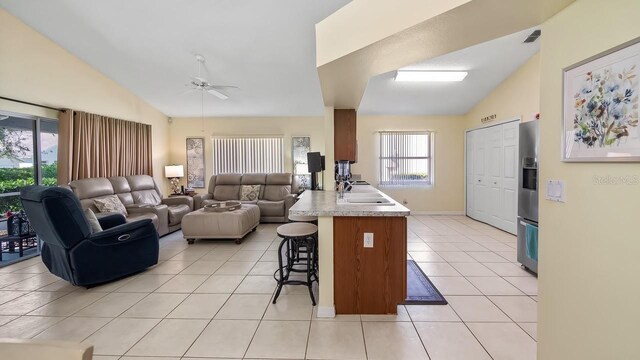 3773 Eversholt St, Clermont, FL 34711 - kitchen with lofted ceiling, a breakfast bar area, light tile patterned floors, and a peninsula