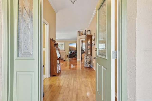 entryway with light wood-style flooring, baseboards, and ornamental molding