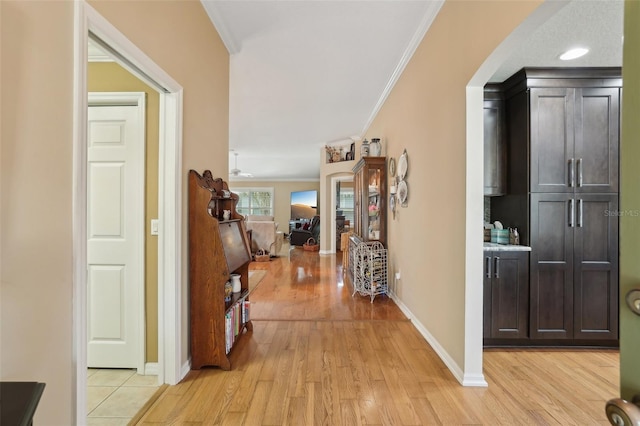 hallway featuring light wood-type flooring, baseboards, and crown molding