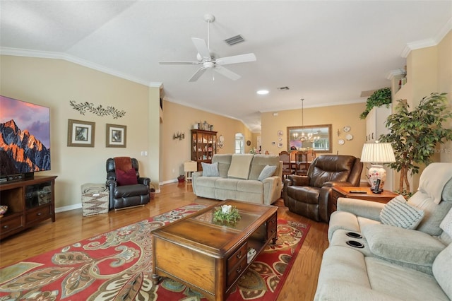 living area with visible vents, lofted ceiling, ornamental molding, ceiling fan with notable chandelier, and wood finished floors