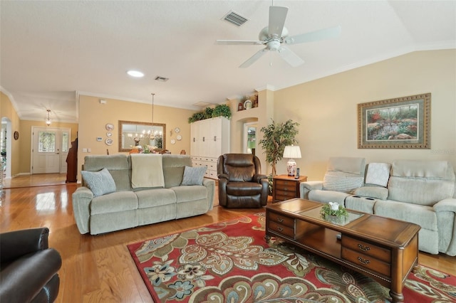 living room with vaulted ceiling, visible vents, crown molding, and wood finished floors