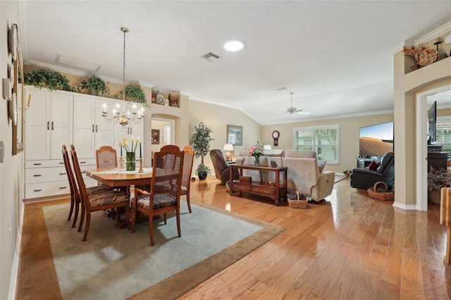 dining space featuring visible vents, crown molding, a chandelier, vaulted ceiling, and light wood-style flooring