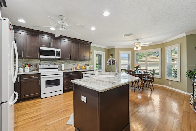 kitchen featuring a sink, decorative backsplash, white appliances, and light wood finished floors