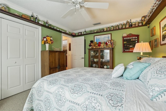 carpeted bedroom featuring visible vents, a closet, ceiling fan, and ornamental molding