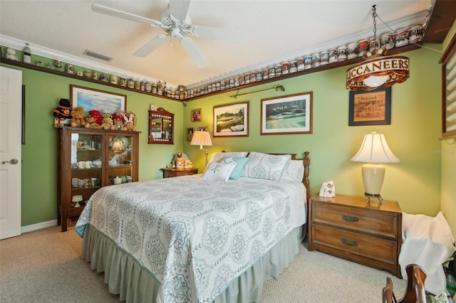 bedroom featuring visible vents, crown molding, baseboards, carpet flooring, and a ceiling fan