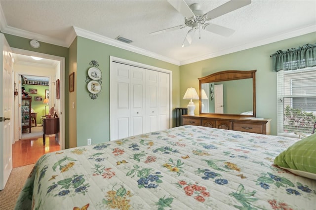 bedroom featuring visible vents, ceiling fan, ornamental molding, wood finished floors, and a closet