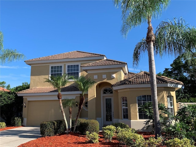 mediterranean / spanish house featuring a tiled roof, driveway, and stucco siding