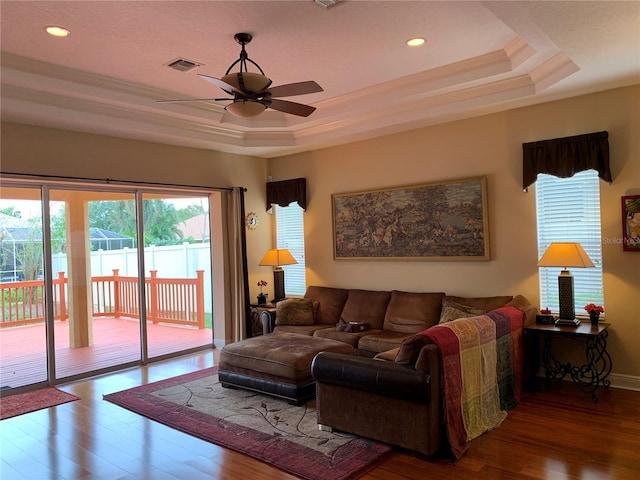 living area with visible vents, crown molding, recessed lighting, wood finished floors, and a raised ceiling