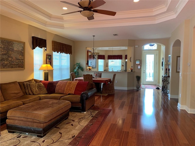 living room featuring a raised ceiling, plenty of natural light, crown molding, and dark wood-type flooring