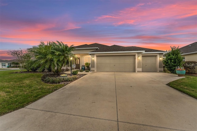 view of front facade featuring concrete driveway, a lawn, an attached garage, and stucco siding