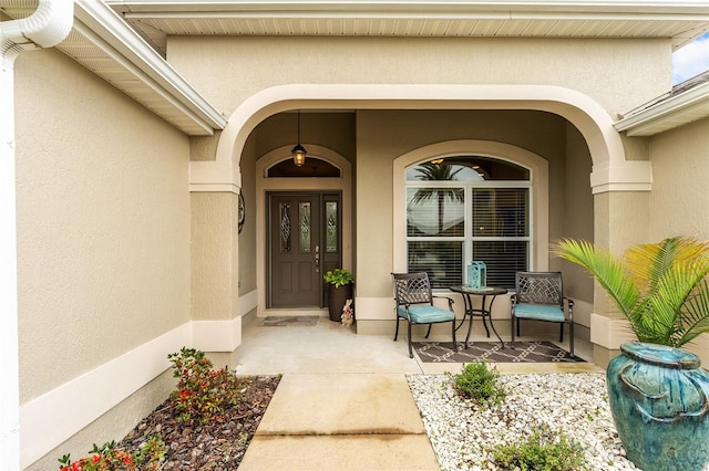 entrance to property with covered porch and stucco siding